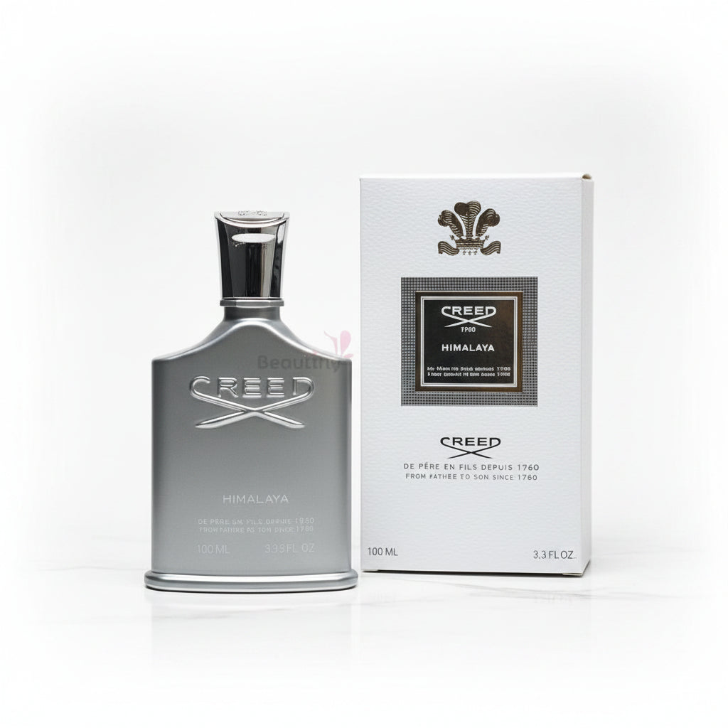 Creed Himalaya perfume bottle and packaging on a textured surface with flowers in the background.