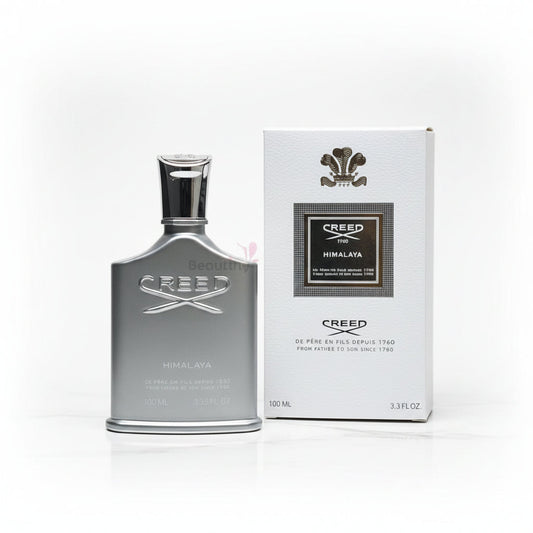 Creed Himalaya perfume bottle and packaging on a textured surface with flowers in the background.